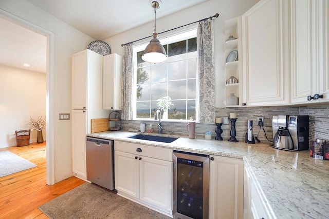 kitchen with light wood-type flooring, beverage cooler, a sink, tasteful backsplash, and stainless steel dishwasher