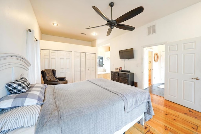 bedroom featuring visible vents, multiple closets, connected bathroom, and light wood finished floors