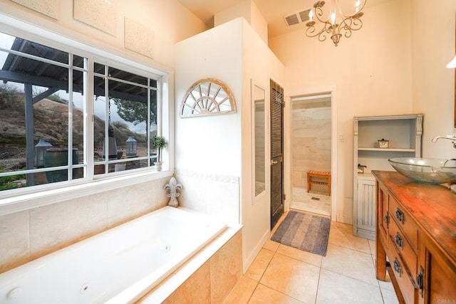 bathroom featuring visible vents, a notable chandelier, a tub with jets, tile patterned flooring, and vanity