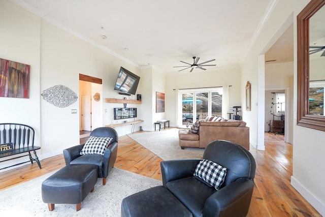 living room featuring crown molding, baseboards, ceiling fan, hardwood / wood-style flooring, and a glass covered fireplace