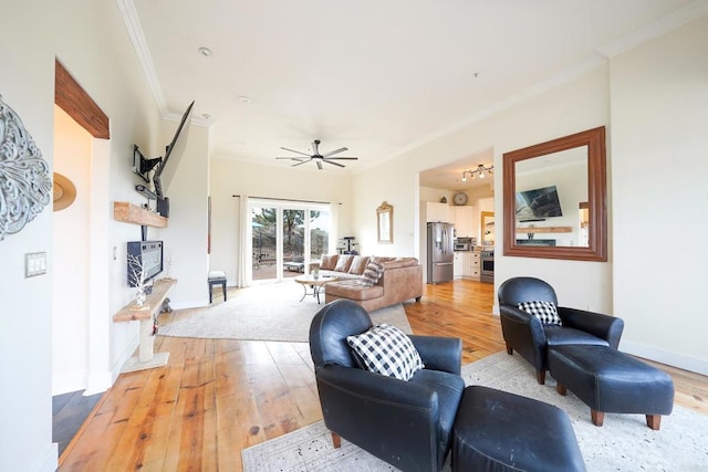 living area with baseboards, light wood-style flooring, and crown molding