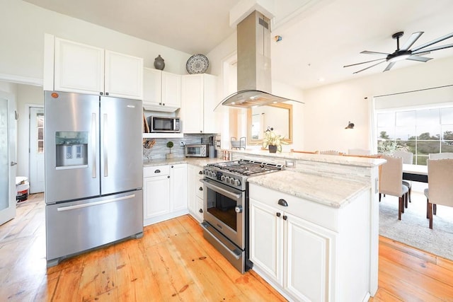 kitchen featuring light wood-type flooring, light stone counters, appliances with stainless steel finishes, a peninsula, and island range hood