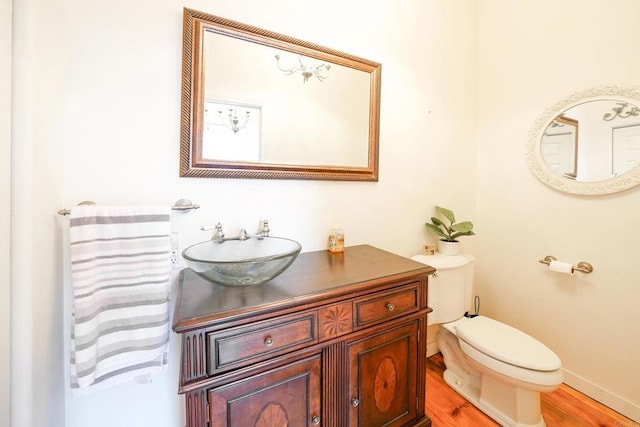 bathroom with vanity, toilet, wood finished floors, and baseboards