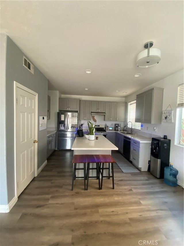 kitchen featuring a sink, a kitchen breakfast bar, appliances with stainless steel finishes, and gray cabinetry