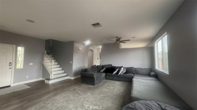 living area featuring wood finished floors, visible vents, arched walkways, ceiling fan, and stairs