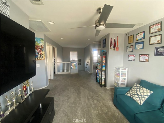 living area featuring baseboards, visible vents, attic access, and ceiling fan