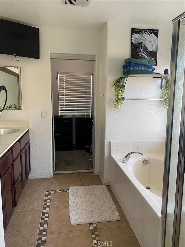 bathroom with vanity, baseboards, visible vents, tile patterned floors, and a bath