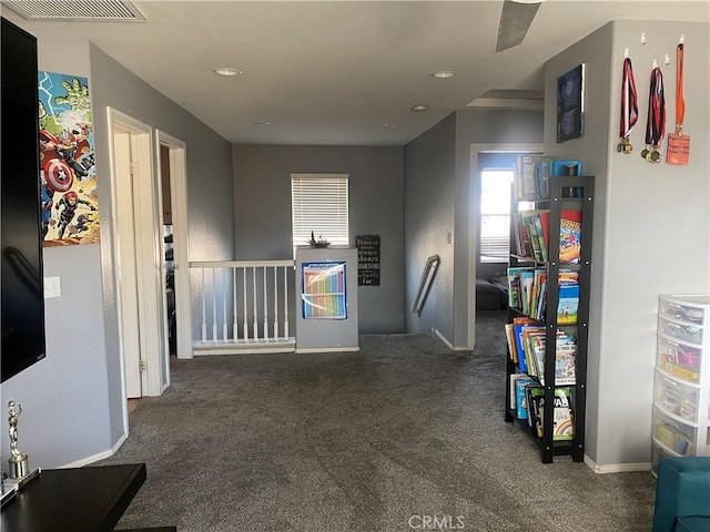 hallway with carpet flooring, an upstairs landing, visible vents, and baseboards