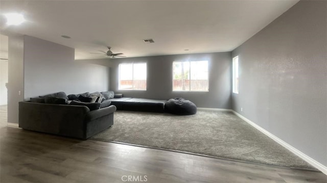 living area with wood finished floors, a ceiling fan, visible vents, and baseboards