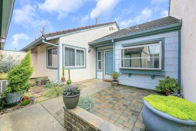 rear view of property with a tiled roof, stucco siding, and a patio area