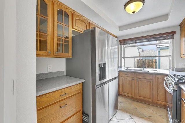 kitchen with a sink, stainless steel appliances, brown cabinets, and glass insert cabinets