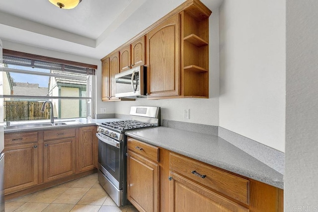 kitchen featuring a sink, light tile patterned floors, appliances with stainless steel finishes, brown cabinetry, and open shelves