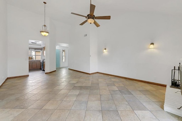 unfurnished living room featuring visible vents, baseboards, a towering ceiling, and ceiling fan