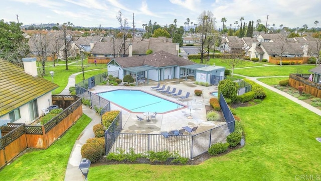 community pool featuring fence, a patio area, a residential view, and a lawn