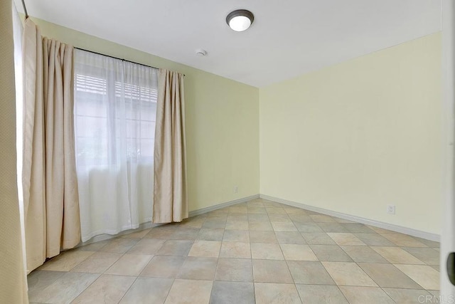 empty room with light tile patterned floors and baseboards