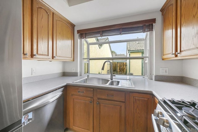 kitchen with brown cabinets, appliances with stainless steel finishes, light countertops, and a sink