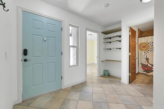 foyer entrance with light tile patterned floors and baseboards