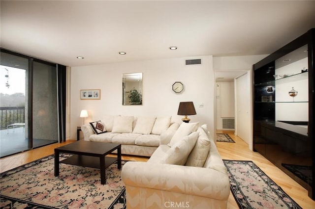 living area with expansive windows, recessed lighting, visible vents, and light wood-type flooring