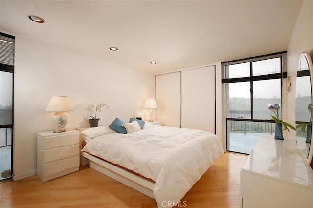 bedroom with floor to ceiling windows, recessed lighting, light wood-style floors, a closet, and access to outside