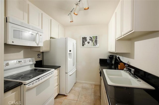 kitchen featuring dark countertops, baseboards, light tile patterned flooring, white appliances, and a sink