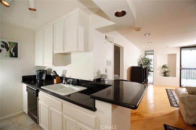 kitchen with dark countertops, white cabinets, black dishwasher, and a sink