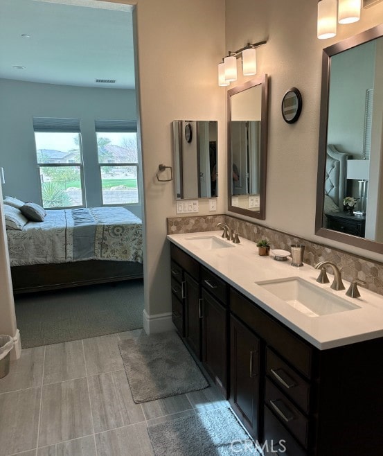 full bath featuring a sink, tasteful backsplash, ensuite bath, and double vanity