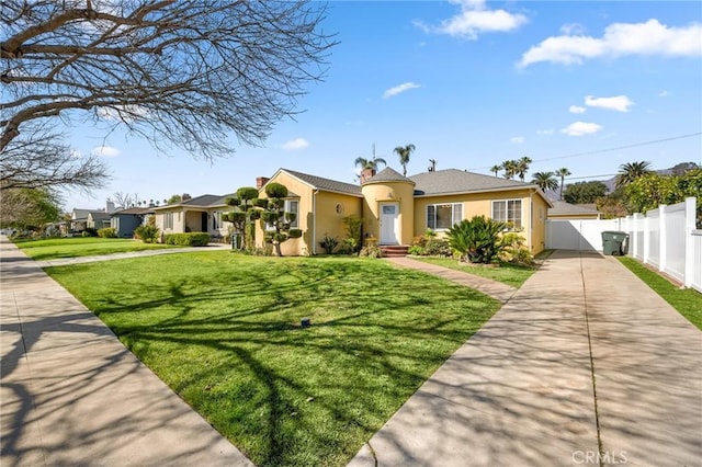 view of front facade with stucco siding, concrete driveway, a front lawn, and fence