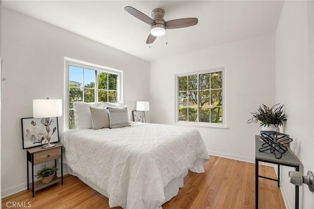 bedroom with a ceiling fan, light wood-type flooring, and baseboards