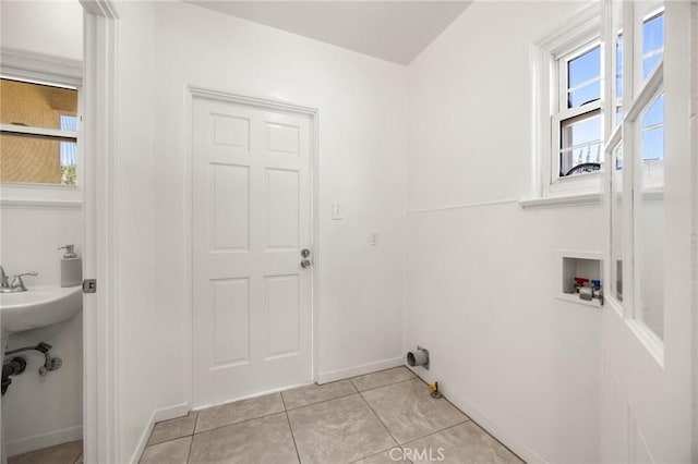 clothes washing area with light tile patterned floors, laundry area, hookup for a washing machine, and baseboards