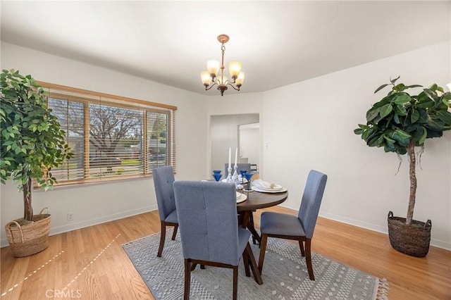 dining space featuring baseboards, an inviting chandelier, and wood finished floors