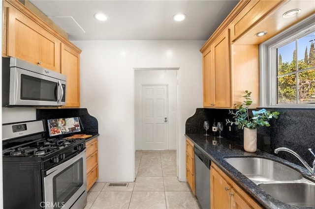 kitchen with visible vents, backsplash, light brown cabinetry, stainless steel appliances, and a sink