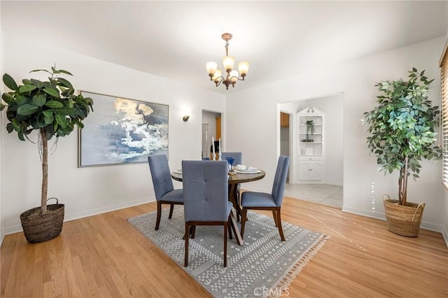 dining area with baseboards, light wood-style floors, and an inviting chandelier