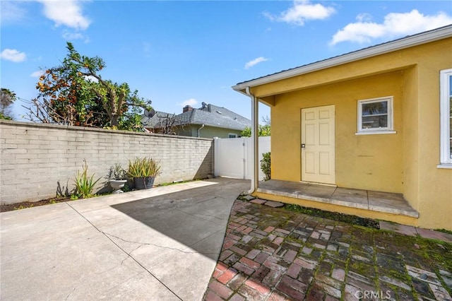 exterior space with a gate, stucco siding, a patio, and fence