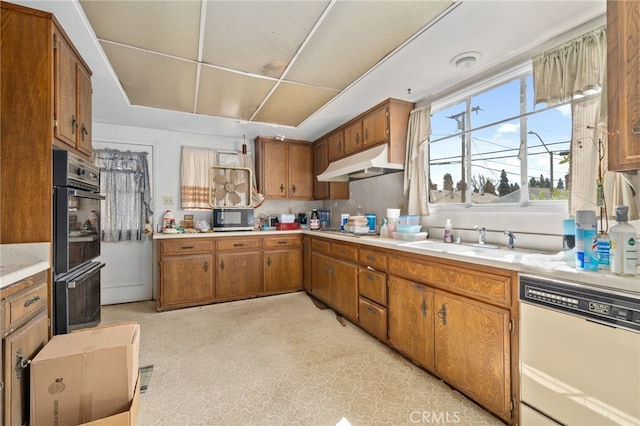 kitchen with stainless steel microwave, under cabinet range hood, light countertops, brown cabinets, and white dishwasher