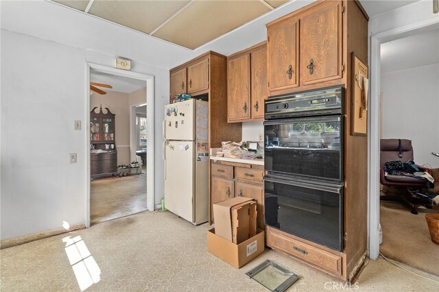 kitchen with baseboards, light countertops, brown cabinets, freestanding refrigerator, and dobule oven black