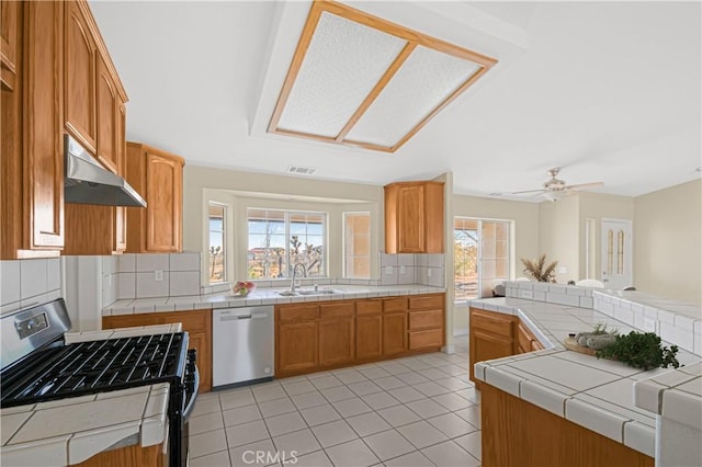 kitchen featuring visible vents, a sink, stainless steel appliances, tile counters, and under cabinet range hood