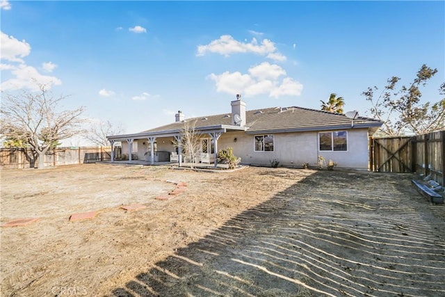 back of property with a tiled roof, stucco siding, a chimney, a fenced backyard, and a patio area