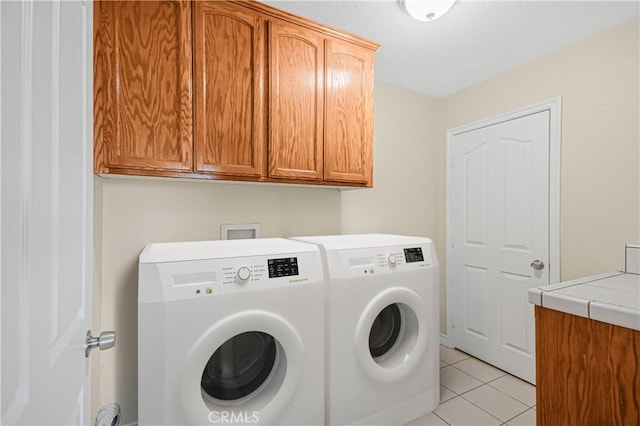 laundry room with light tile patterned floors, cabinet space, and washing machine and dryer