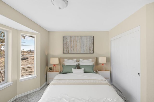 carpeted bedroom featuring a closet and baseboards