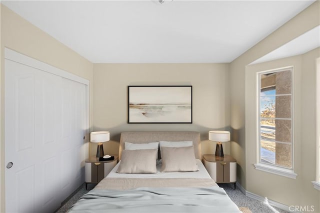 carpeted bedroom with a closet and baseboards