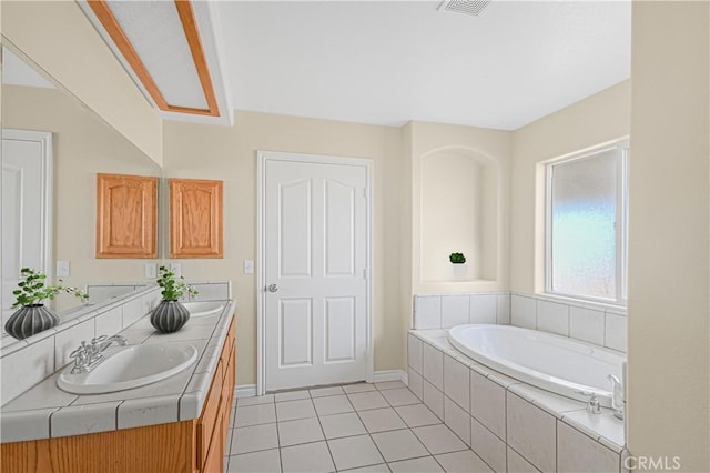 full bath featuring tile patterned flooring, baseboards, double vanity, a bath, and a sink