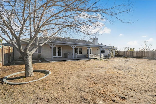 back of house featuring stucco siding, a fenced backyard, french doors, a chimney, and a patio area