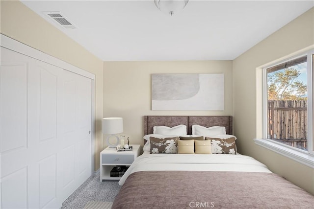 carpeted bedroom with visible vents and a closet