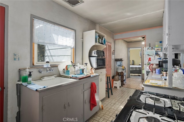 kitchen featuring stovetop, brick floor, and a sink