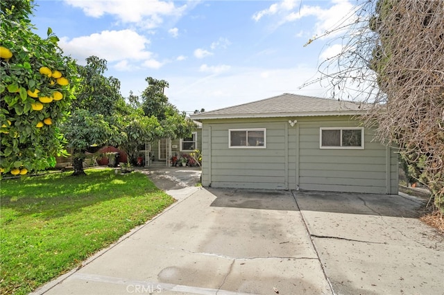 back of property featuring a patio area, a lawn, and roof with shingles