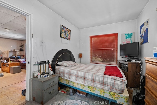 bedroom with a paneled ceiling and wood finished floors