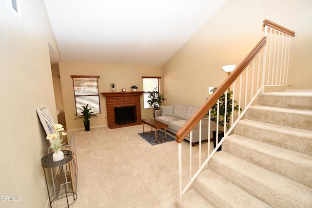 living room with baseboards, carpet floors, a fireplace, stairs, and vaulted ceiling