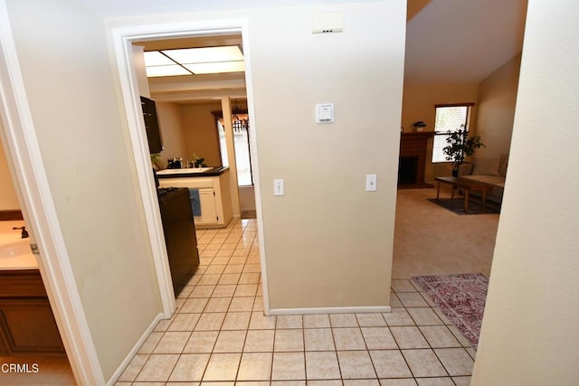 hallway with light tile patterned floors, light colored carpet, and baseboards