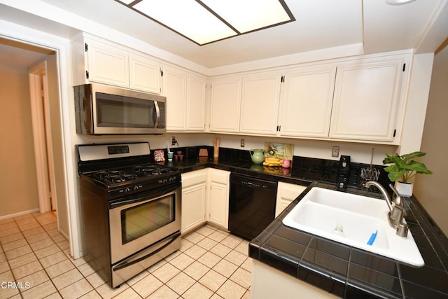 kitchen with light tile patterned flooring, white cabinets, appliances with stainless steel finishes, and a sink