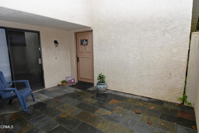 property entrance featuring stucco siding and a patio